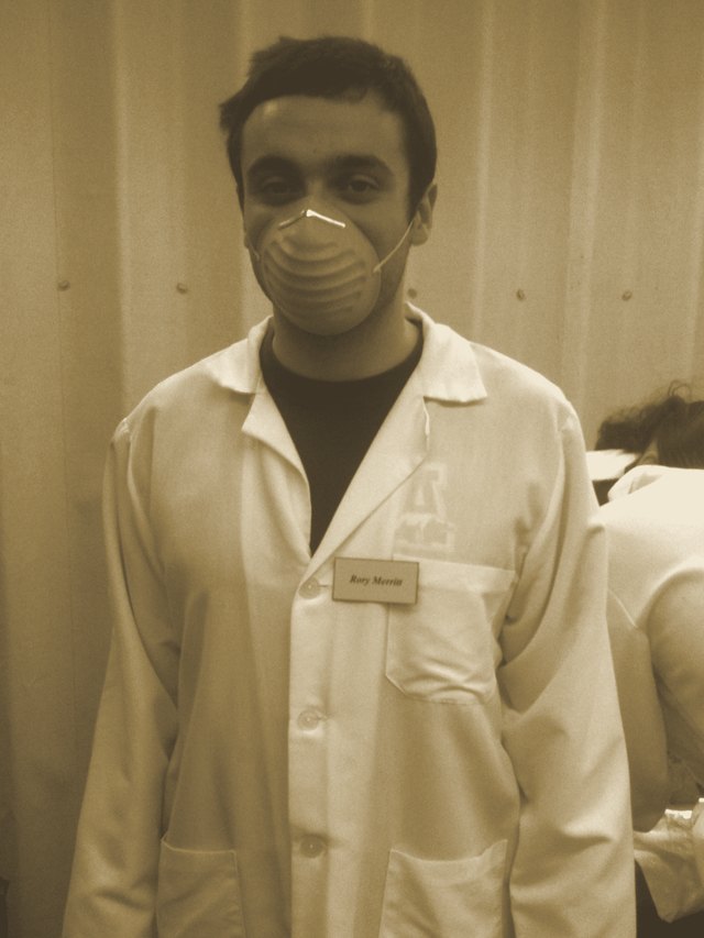 Rory in medical school, masked and gloved in a lab coat for gross anatomy